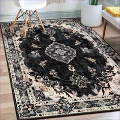 a black rug with an ornate design on the center and bottom, in front of a white chair