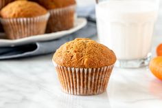 a muffin sitting on top of a table next to oranges and a glass of milk