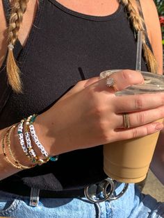 a woman holding a coffee cup and wearing bracelets