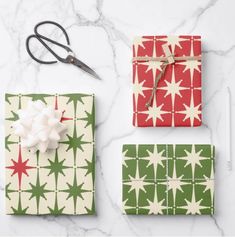 three wrapped presents are sitting on a marble counter top with scissors and other holiday decorations