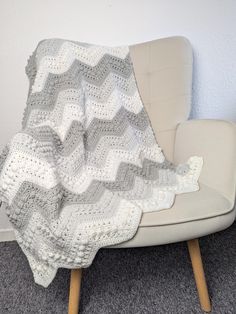 a white crocheted blanket sitting on top of a chair next to a wall