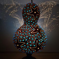 an illuminated vase sitting on top of a table next to a wall with stars in it