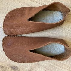 the inside of a pair of brown shoes on top of a wooden floor next to a white ball