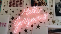 a neon sign that says hell's gorgeous surrounded by photos and stars on the wall