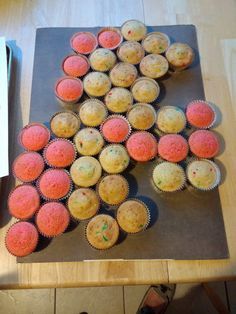 a table topped with lots of pink and yellow cupcakes