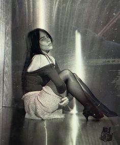 a woman sitting on the floor with her legs crossed wearing stockings and high heeled boots