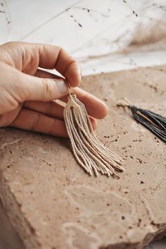 a person is holding some tassels on a piece of stone