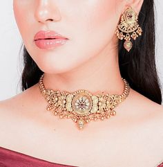 India necklace from Amrapali. This exquisite piece showcases the timeless allure of antique choker designs with a touch of Kundan jewelry elegance. Crafted with precision, it boasts intricate detailing and bears the hallmark of South India's rich jewelry tradition. This gold necklace is a testament to Amrapali's artistry in temple jewelry. Wear it to embody the grace and opulence of India's cultural heritage wherever you go. *𝐏𝐑𝐎𝐃𝐔𝐂𝐓 𝐃𝐄𝐓𝐀𝐈𝐋* * Material: Brass * Plating: Gold Plated 22k Gold Jewelry For Puja, Elegant Jewelry For Navratri Puja, 22k Gold Tilla Jewelry For Navratri, Elegant Jewelry For Puja And Navratri, 22k Gold Cutdana Jewelry For Puja, Bollywood Style 22k Gold Jewelry For Navratri, Gold Jewelry With Cutdana For Navratri, Kundan Jewelry With Motifs For Navratri, Yellow Gold Cutdana Jewelry For Navratri