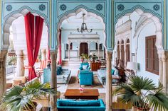 a living room filled with blue couches and lots of windows covered in red drapes