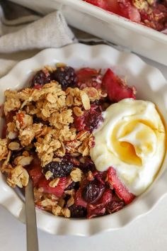 a bowl filled with granola, fruit and yogurt on top of a white plate