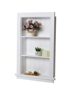 a white book shelf with flowers and candles on the bottom shelf, against a white background