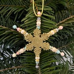 a gold snowflake ornament hanging from a christmas tree with beaded beads