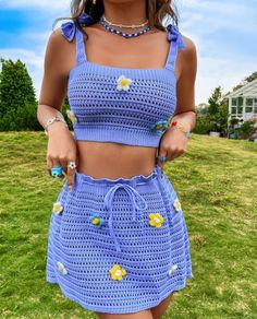 a woman standing in the grass wearing a crop top and shorts