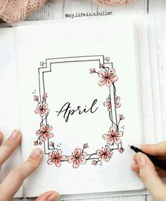 two hands holding a notebook with the word april written on it and flowers around them