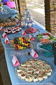 a table topped with lots of food on top of a blue cloth covered tablecloth