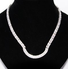 This is a fabulous Silver and Cubic Zirconia necklace. The design is absolutely stunning with alternate sections of six and four leaves encrusted with bright Cubic Zirconia stones. Each section is securely attached to the next and moves with a snake like fashion. The front section has a 'U' shape, this is rigid so holds its shape permanently. The necklace has been beautifully crafted. The catch has a safe and secure push-in catch. The necklace measures 43cm long and 0.6cm wide. It is stamped 925 Elegant Cubic Zirconia Tennis Necklace With Bling, Formal Fine Jewelry Necklaces With Bling, Formal Bling Fine Jewelry Necklaces, Formal White Gold Necklace With Bling, Formal White Gold Bling Necklace, Herringbone Design, Zirconia Necklace, Cubic Zirconia Necklace, The Catch