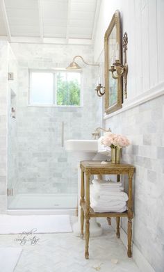 a bathroom with a sink, mirror and shower stall in the corner is white marble