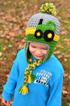 a young boy wearing a crocheted hat with a green and yellow tractor on it