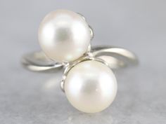 This luxurious pearl ring has a classical bypass style that is timeless! The pearls sit in the center of curving, polished heads in gleaming 14 karat white gold. Easy to wear day or night, this vintage ring is elegant and beautiful. Metal: 14K White Gold Gem: 2 Pearls Gem Measurements: 8 mm, Round Ring Size: 4.25 Marks: "14K" Stamped on the inside band Luxury Elegant Pearl Ring With Round Band, Luxury Classic White Gold Pearl Ring, Luxury Polished Round Cut Pearl Ring, Luxury Vintage White Gold Pearl Ring, Pearl Ring Design, Yellow Gold Sapphire Ring, June Birthstone, Round Rings, White Gold Ring