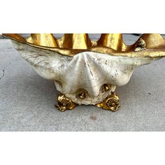 a gold and white vase sitting on top of a sidewalk