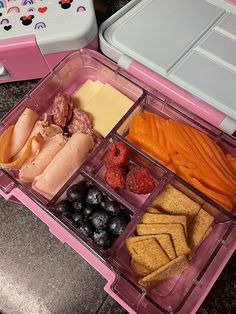 a pink lunch box filled with different types of food and cheeses, crackers, fruit, and meat