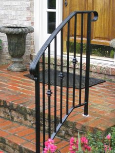 an iron handrail on the steps leading up to a front door with pink flowers