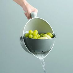 a person is pouring water into a bucket filled with fruit