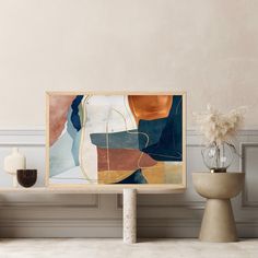 an abstract painting hangs on the wall next to a vase with flowers