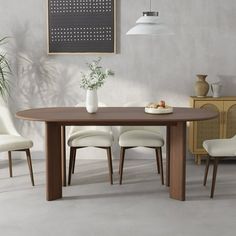 a dining table with white chairs and a plant on it in a room that has gray walls