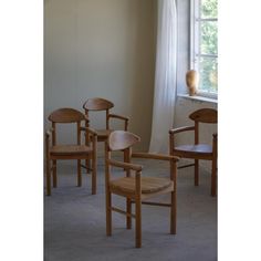 four wooden chairs sitting in front of a window