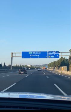 an exit sign on the side of a highway with cars driving underneath it and trees in the background