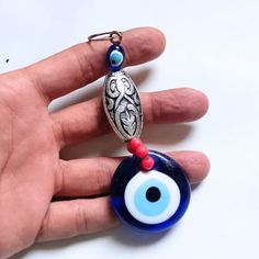 a hand holding a blue and white evil eye keychain on it's thumb