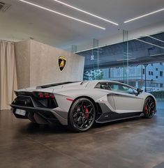 a white and black sports car parked in a garage next to a wall with windows