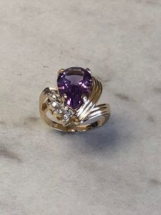 This beautiful 14kt Yellow Gold Lady's Diamond and Amethyst Ring consists of a 10mm x 15mm Genuine Pear Shape Amethyst Gemstone 5.00ct approx total weight and 4 diamond accents .05ct approx total weight all prong set in a fashion swirl solid mounting. Finger size 6 1/2 which can be resized. Amethyst is the Birthstone for February. This item would Retail for $1,250.00 Elegant Teardrop Amethyst Ring, Pear-shaped Purple Amethyst Ring With Prong Setting, Purple Pear-shaped Amethyst Ring With Prong Setting, Purple Teardrop Amethyst Ring For Anniversary, Formal Teardrop Amethyst Ring In Fine Jewelry Style, Fine Jewelry Teardrop Purple Ring, Elegant Teardrop Purple Amethyst Ring, Fine Jewelry Purple Teardrop Ring, Purple Teardrop Fine Jewelry Ring