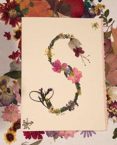 the letter s is made up of flowers and leaves on top of a sheet of paper