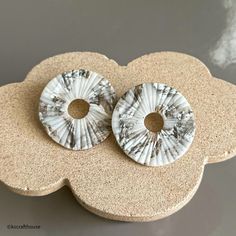 two white and black buttons sitting on top of a stone flower shaped broochle