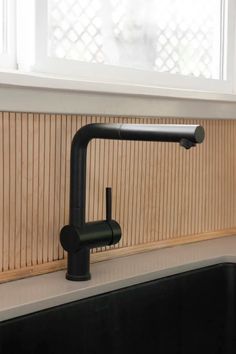 a black faucet sitting on top of a kitchen sink next to a window