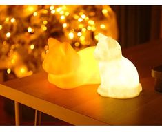 two white and yellow lights sitting on top of a table next to a christmas tree