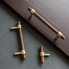 two wooden handles with brass fittings are on the floor next to a piece of wood