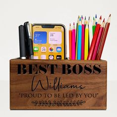 a wooden box filled with lots of different types of pens and pencils next to a cell phone