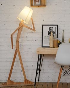 a wooden floor lamp sitting on top of a table next to a white chair and desk