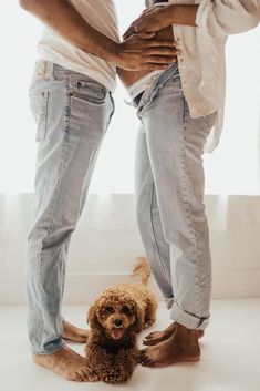 two people standing next to each other with a dog sitting on the floor in front of them