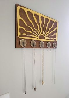 a wooden wall hanging with several necklaces on it