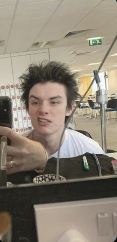 a young man taking a selfie with his cell phone in an office setting,