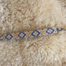 a blue and yellow beaded bracelet laying on top of a sheep's wool