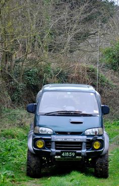 an suv is parked in the grass near some trees