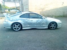 a silver car parked in a parking lot next to a building with graffiti on it