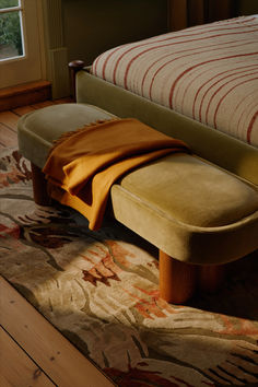 a bench sitting on top of a wooden floor next to a bed