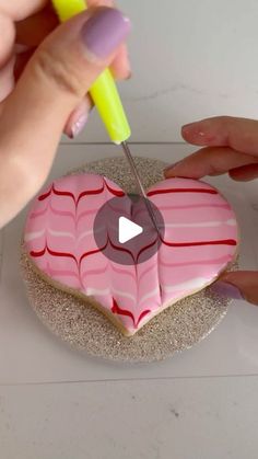 a person cutting into a heart shaped cookie with a sharpie marker on it's side