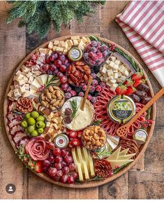 a platter filled with cheese, crackers, nuts and other foods on a wooden table